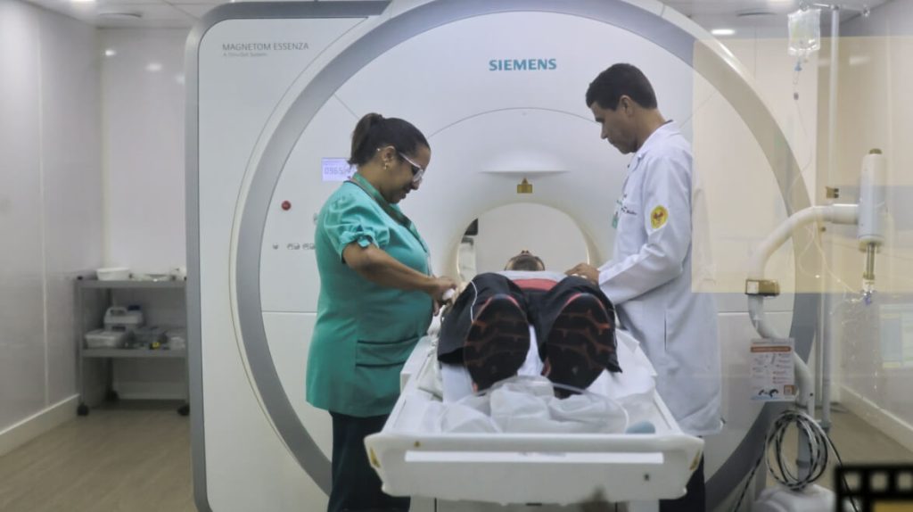Equipe preparando paciente para exame de ressonância magnética em clínica de diagnóstico por imagem
