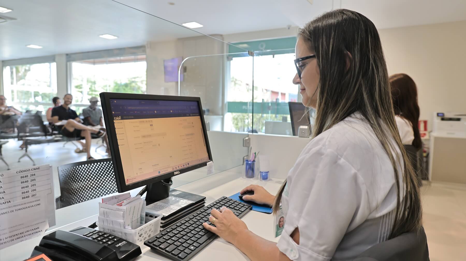 Colaboradora da Lagos Scan realizando atendimento no computador na recepção da clínica em Araruama.