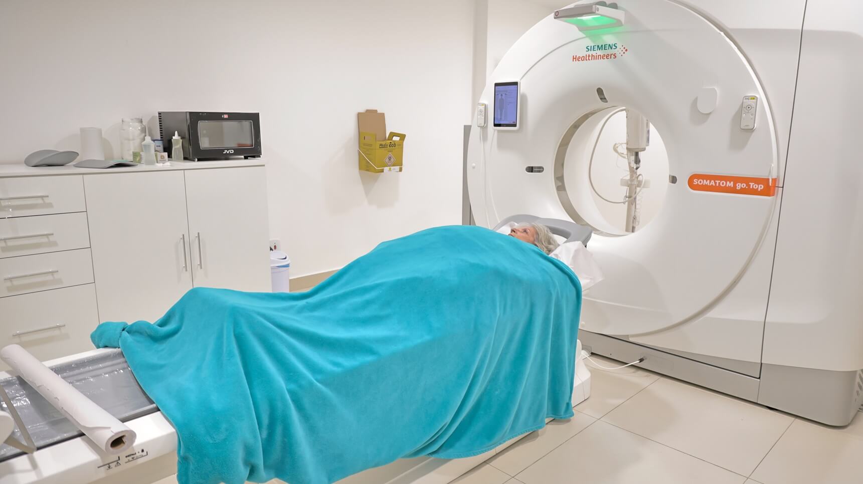 Paciente deitada na maca de exame posicionada em frente ao aparelho de tomografia computadorizada Siemens Somatom na clínica Lagos Scan, em Araruama.