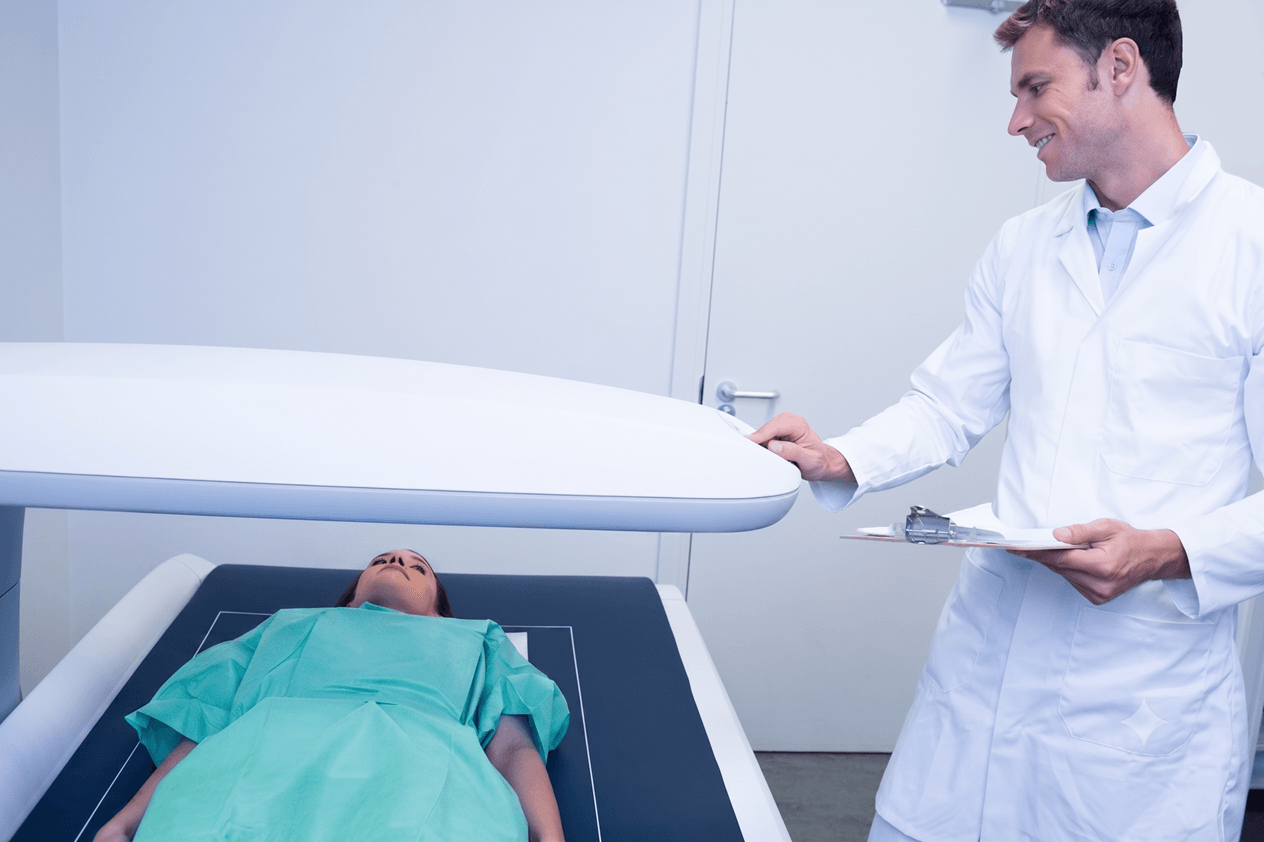 Médico radiologista acompanhando paciente durante a realização do exame de densitometria óssea na clínica Lagos Scan, em Araruama