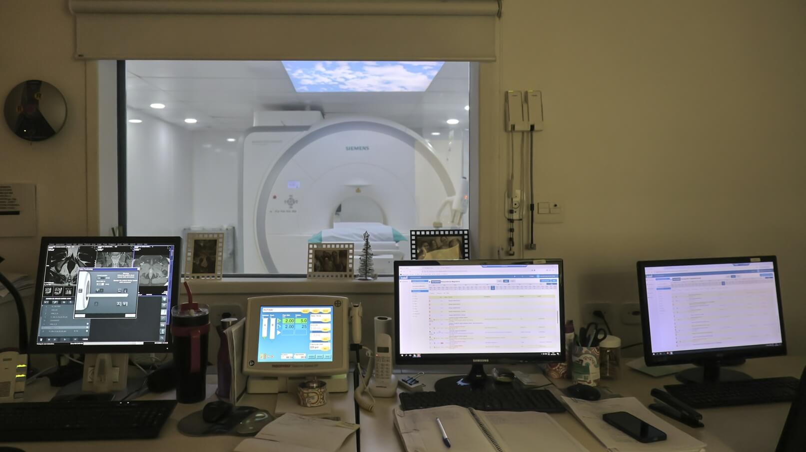Estação de trabalho e sala de comando com monitores de controlo do aparelho de ressonância magnética na clínica Lagos Scan, em Araruama.